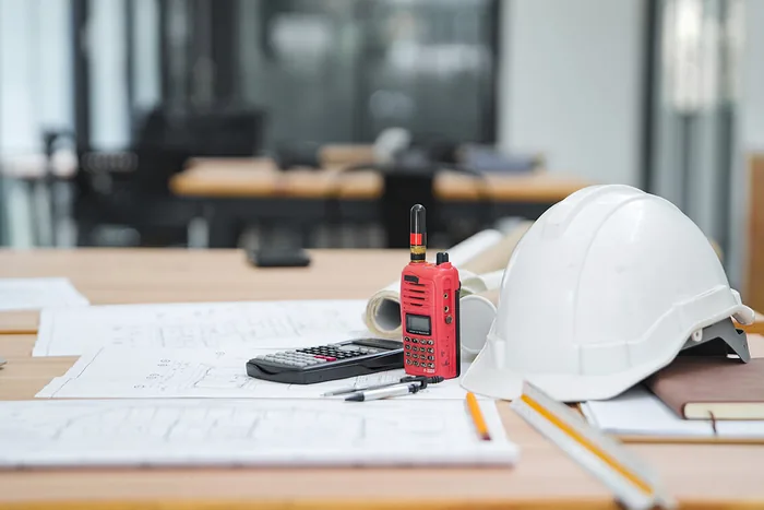 Mesa de trabalho com capacete de segurança, projeto técnico impresso e instrumento de medição